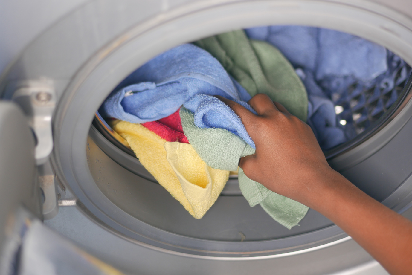 Woman Hand Putting Towels in Washing Machine